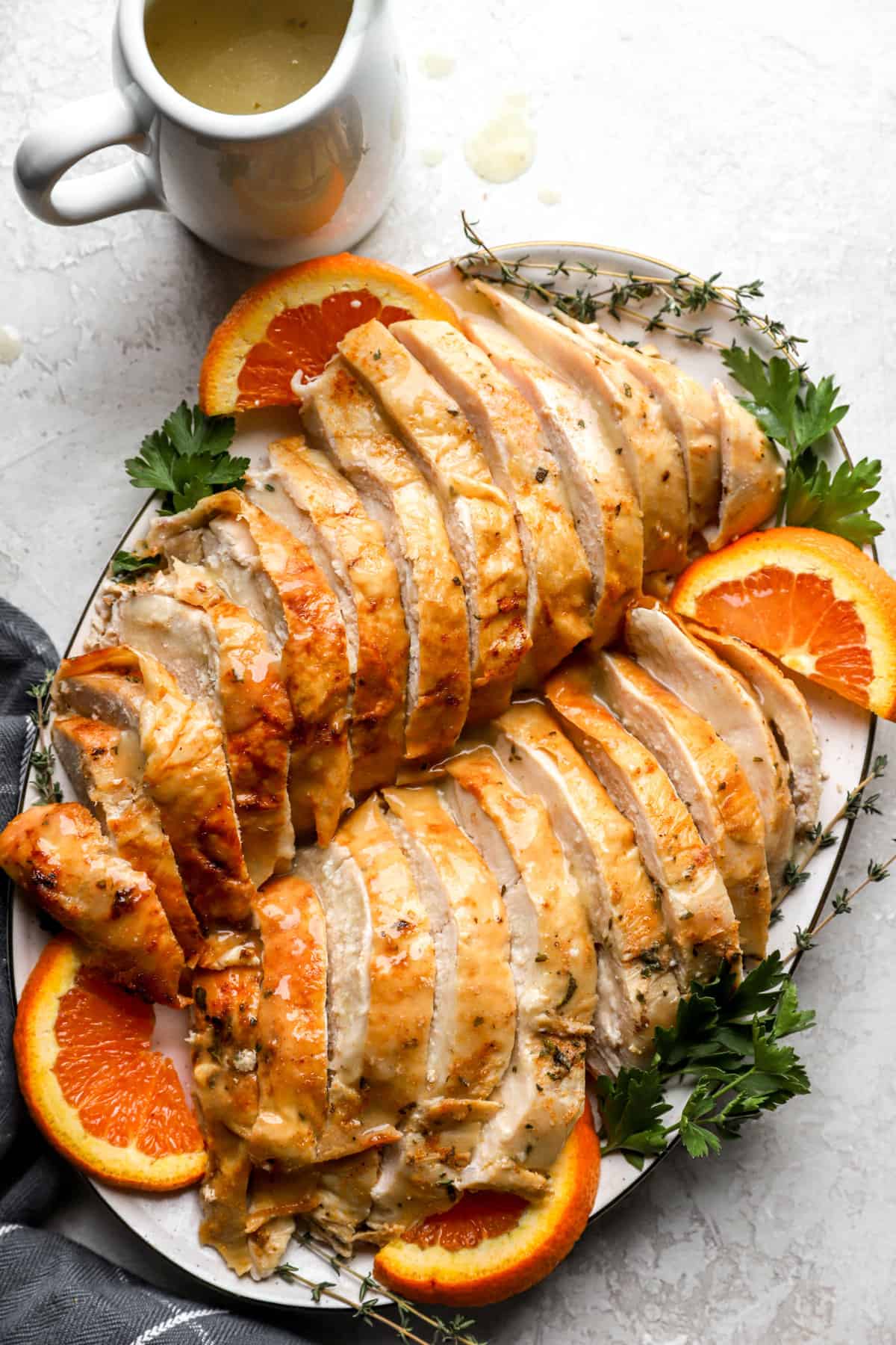 above image of a sliced roasted turkey on a platter garnished with orange slices and greens.
