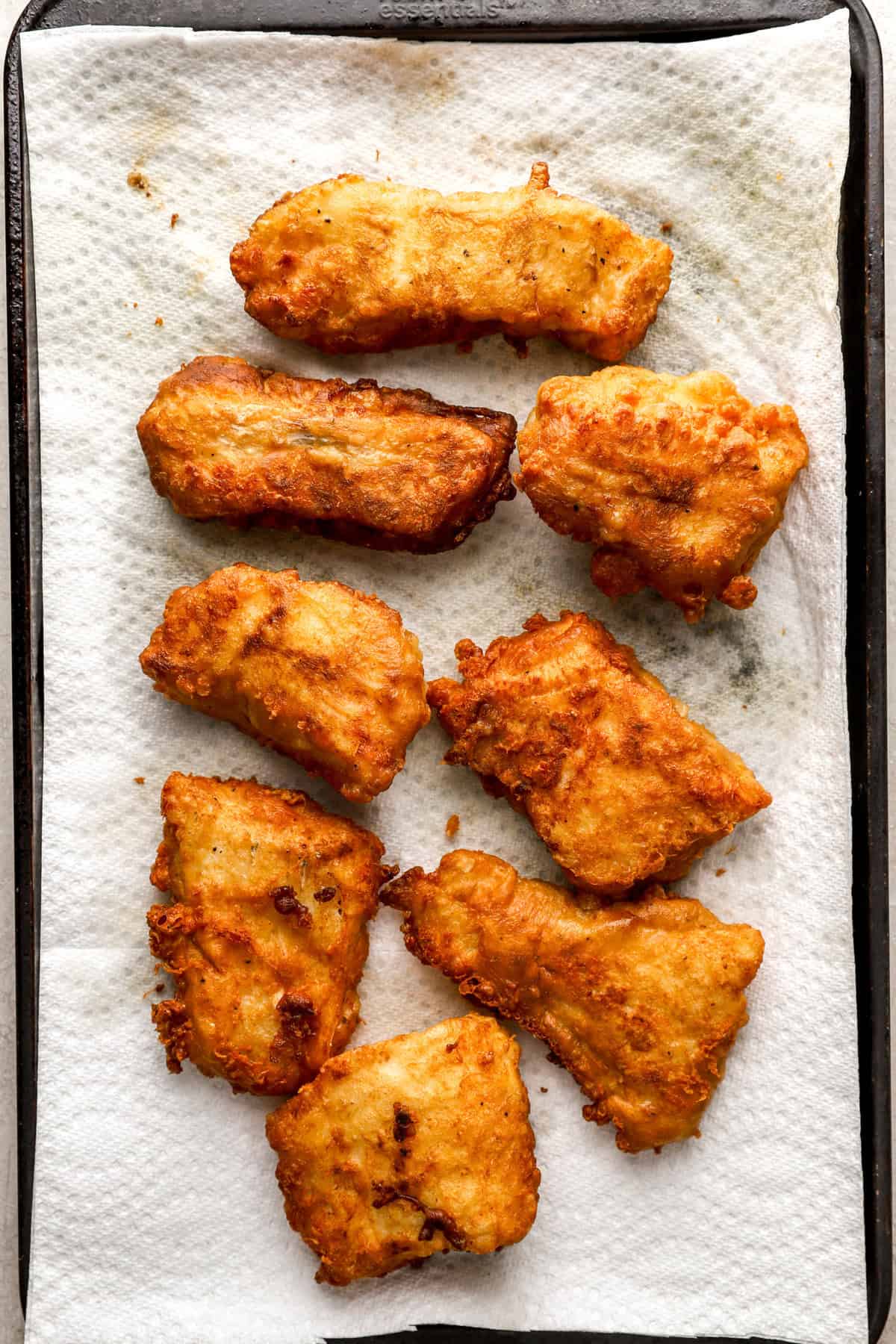 Baked breaded fish filets on a paper towel.