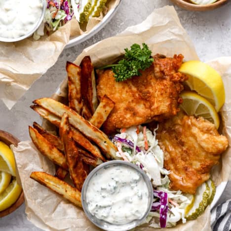 A basket of homemade fish and chips with slaw and tartar sauce.