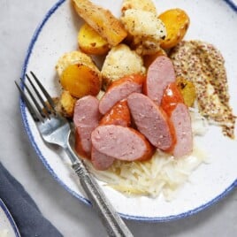 Sheet Pan Sausage and Sauerkraut on a plate with veggies.