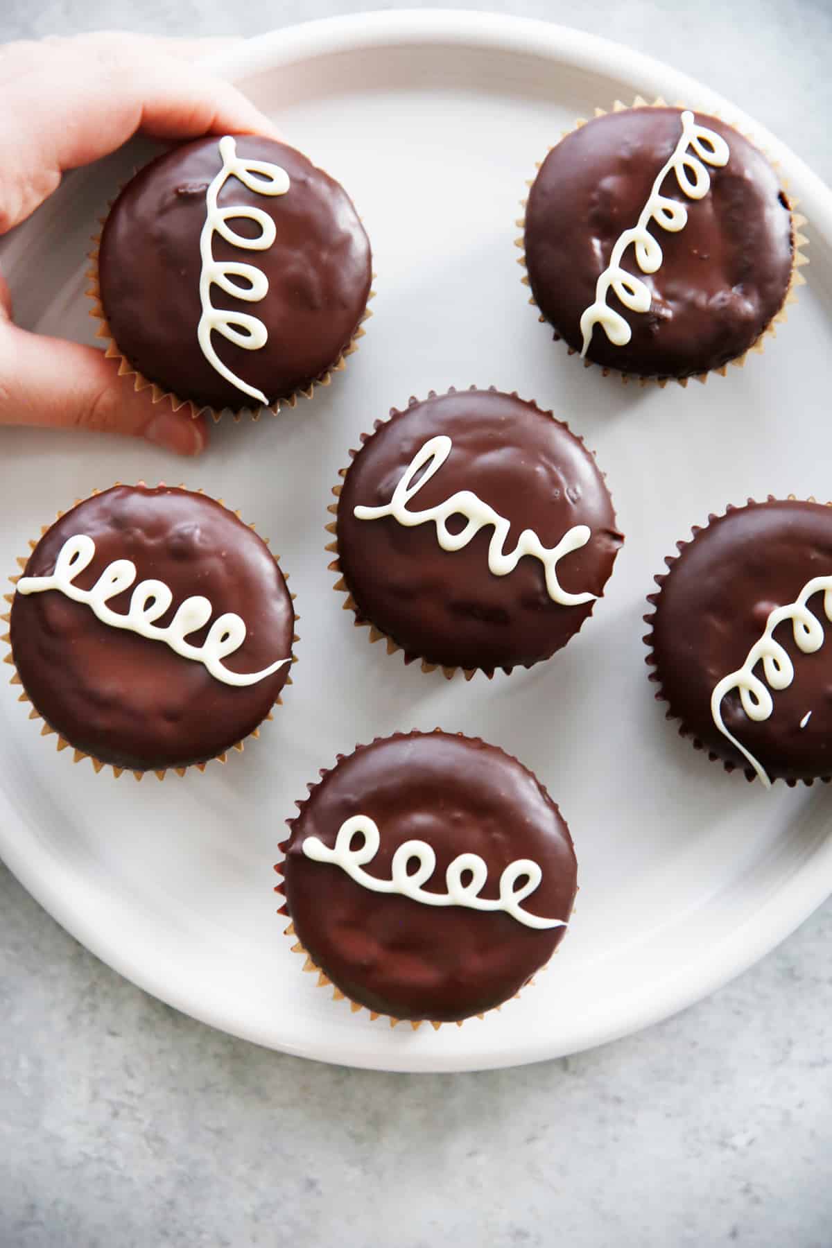 overhead of chocolate hostess cupcakes on a plate with one being taken off.