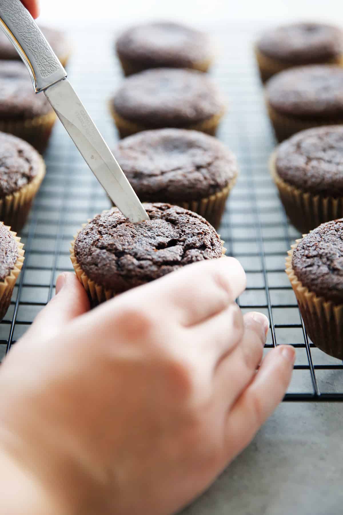 a hole being cut out of the center of a cupcake.