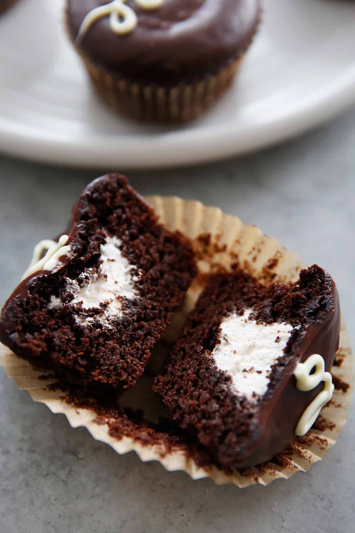 overhead and closeup of a halved hostess cupcake in a cupcake liner.