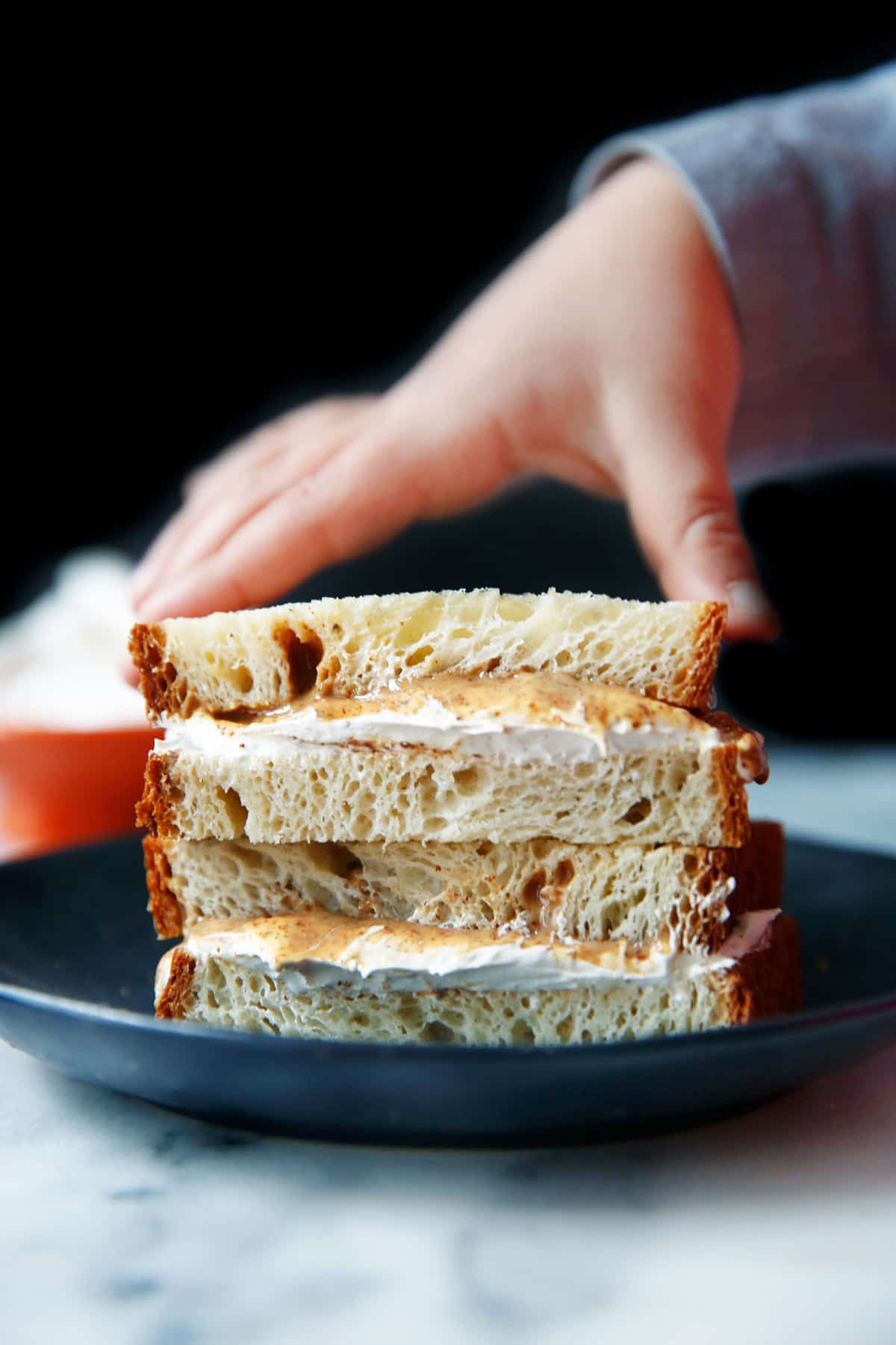 a hand lifted a half of a fluffernutter sandwich off of a plate.