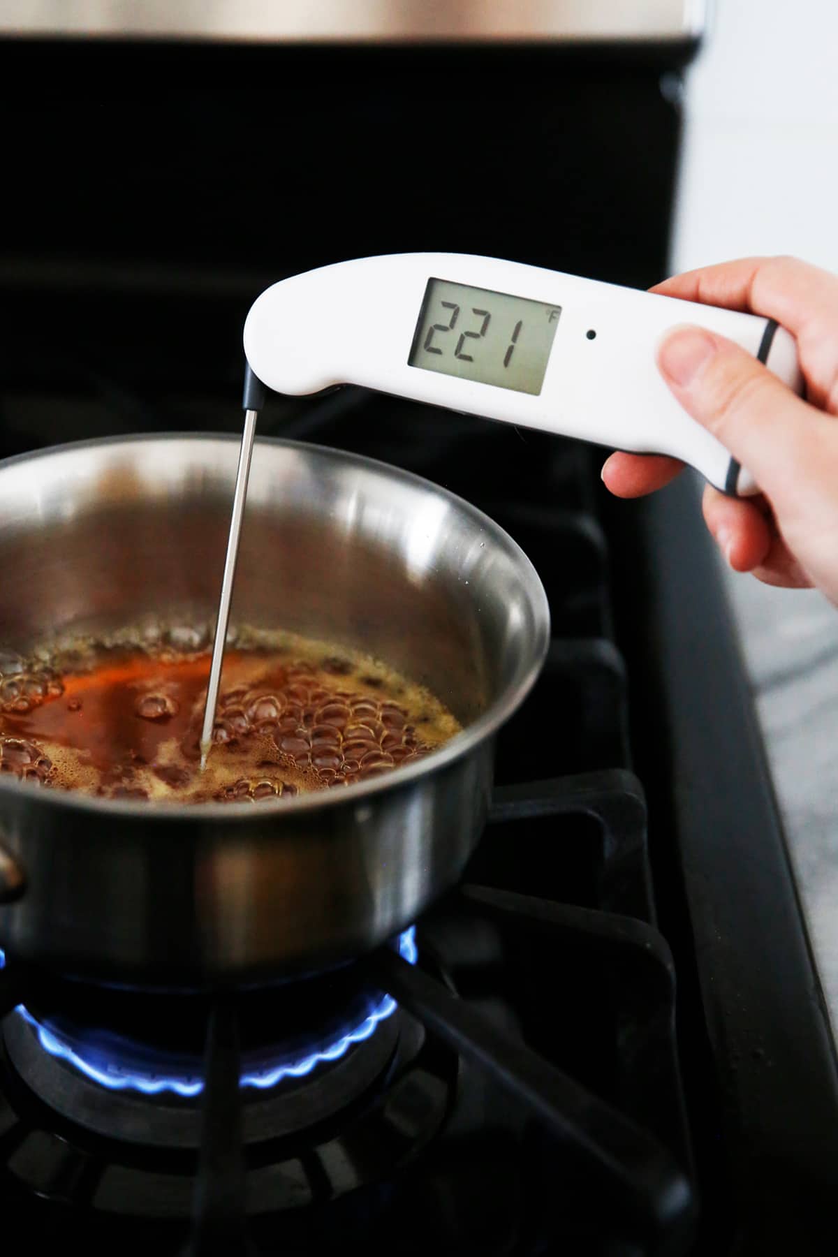 a thermometer being used to measure the temperature of honey, maple syrup, and water.