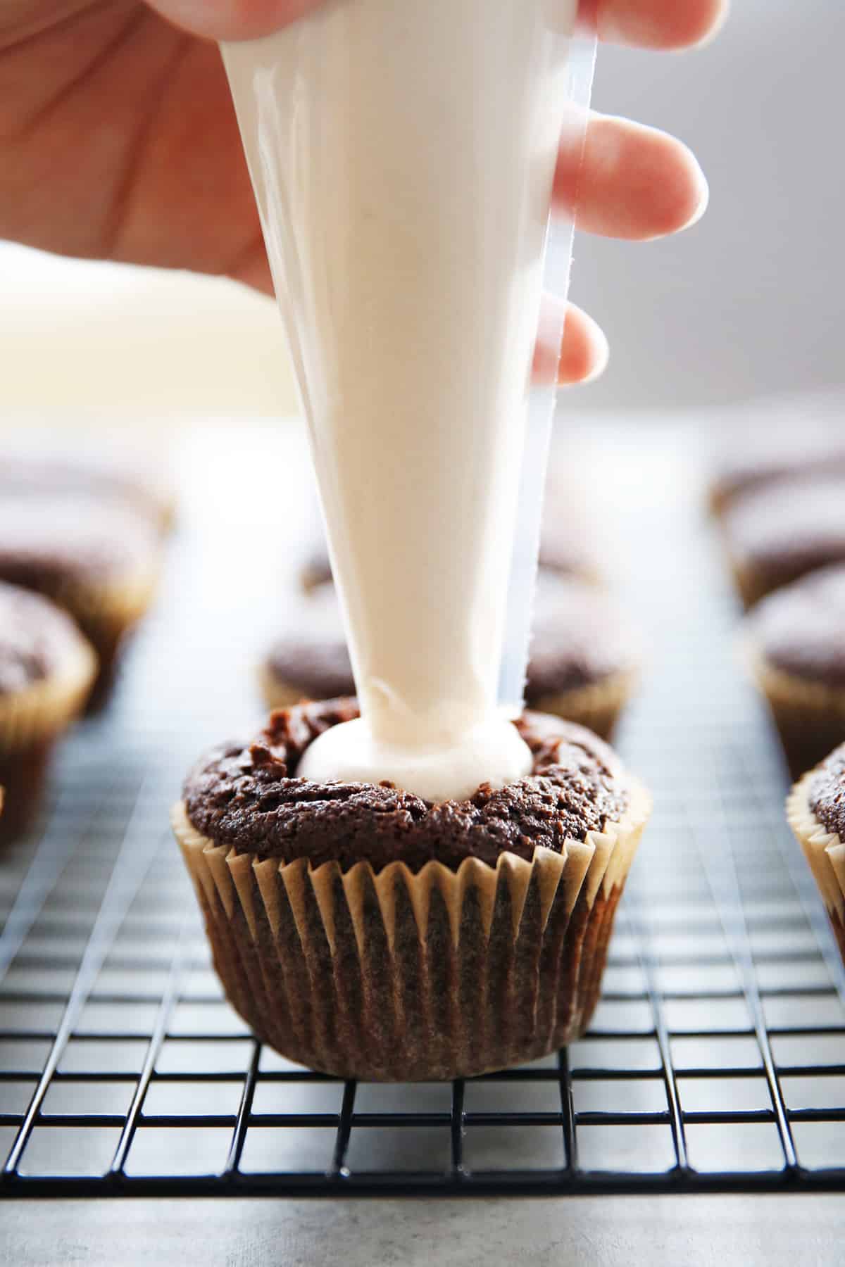 a chocolate cupcake being filled with marshmallow cream.
