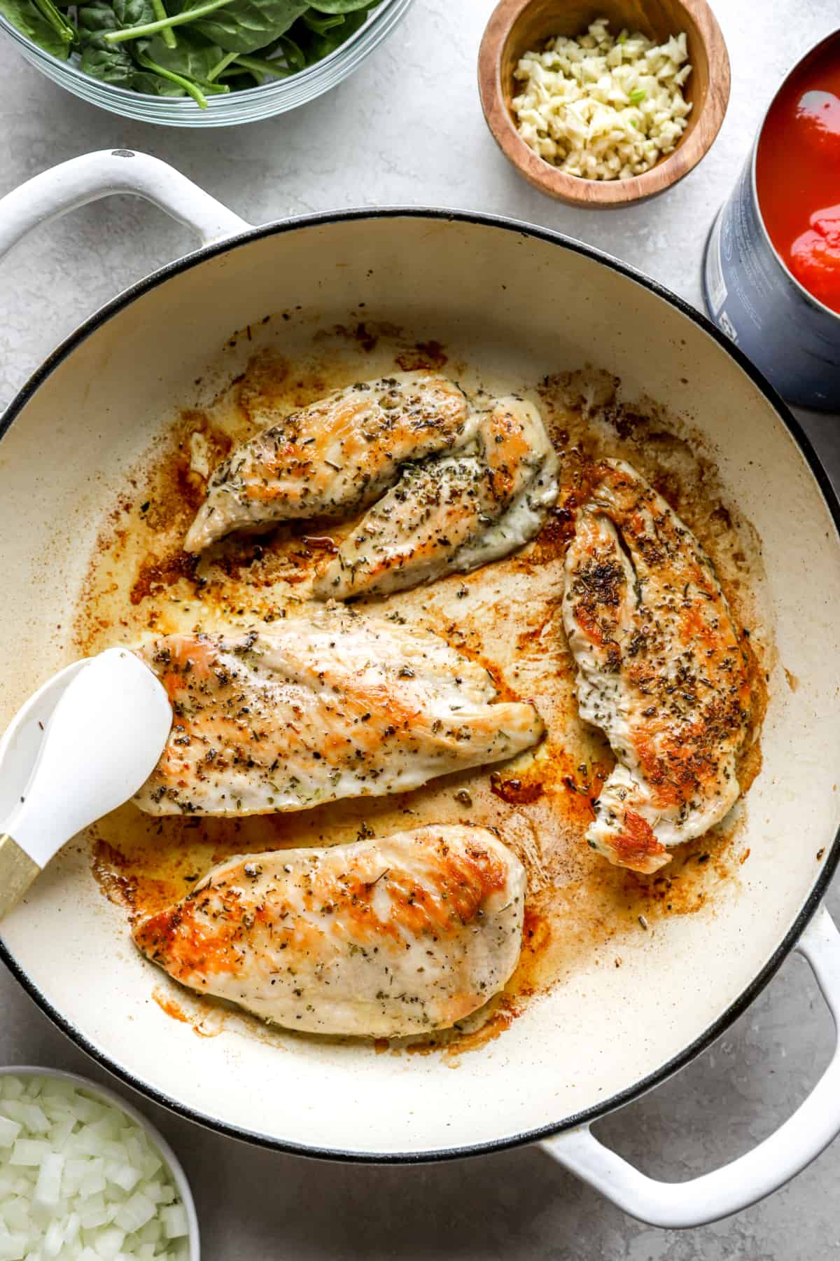 Italian chicken being seared in a pan from above.