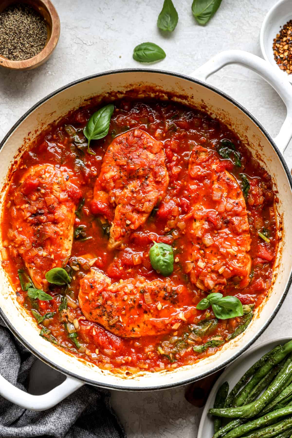 four pieces of chicken covered in tomato sauce in a pan.