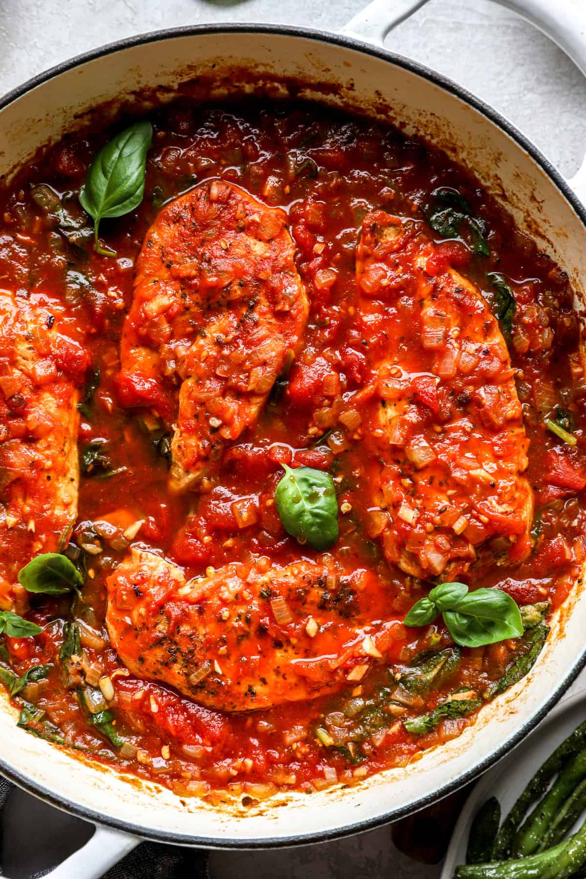 a pan filled with chicken cutlets in tomato sauce with spinach.