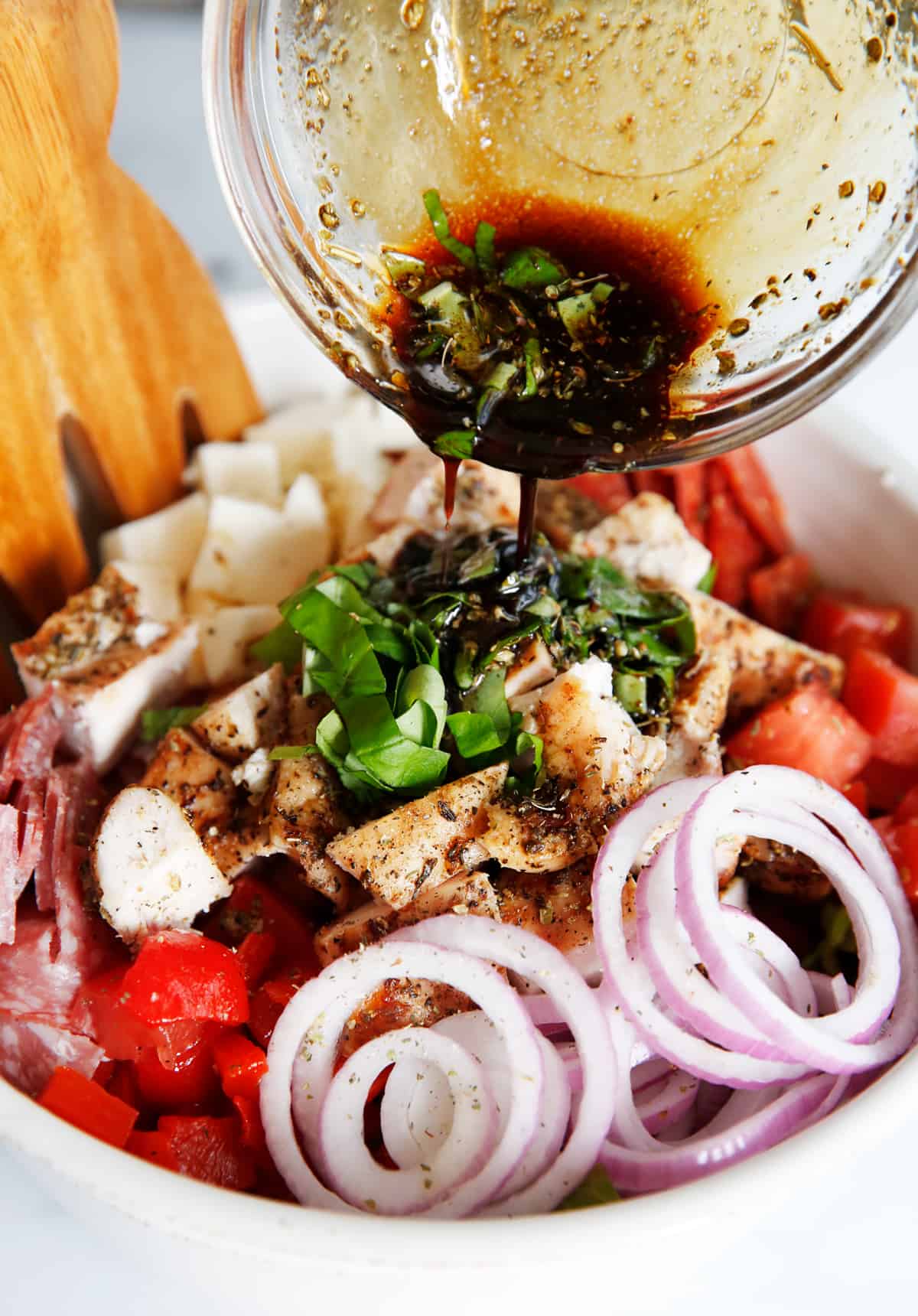 Italian dressing being poured onto antipasto salad.