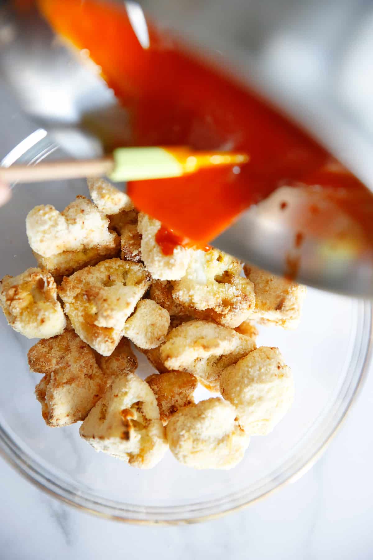 pouring buffalo sauce on low carb spicy cauliflower