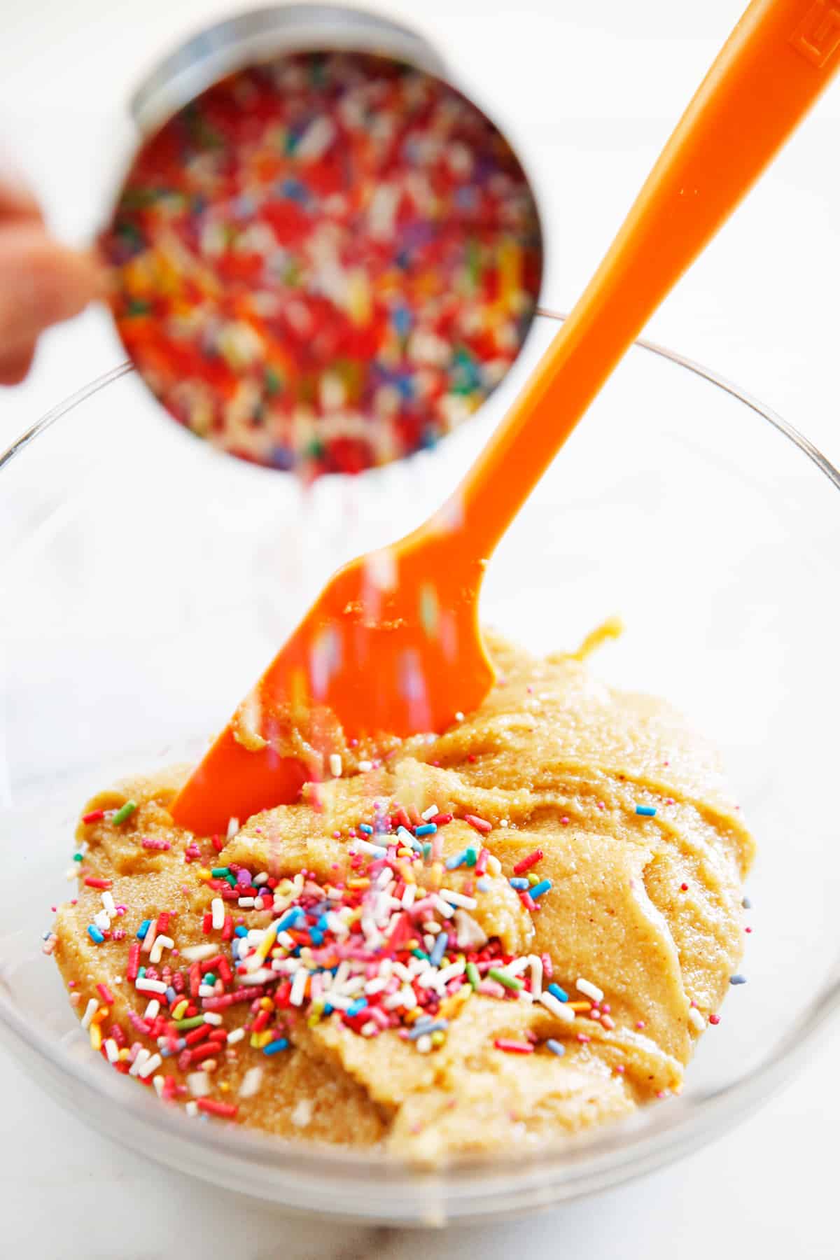 sprinkles getting poured into almond flour blondie batter