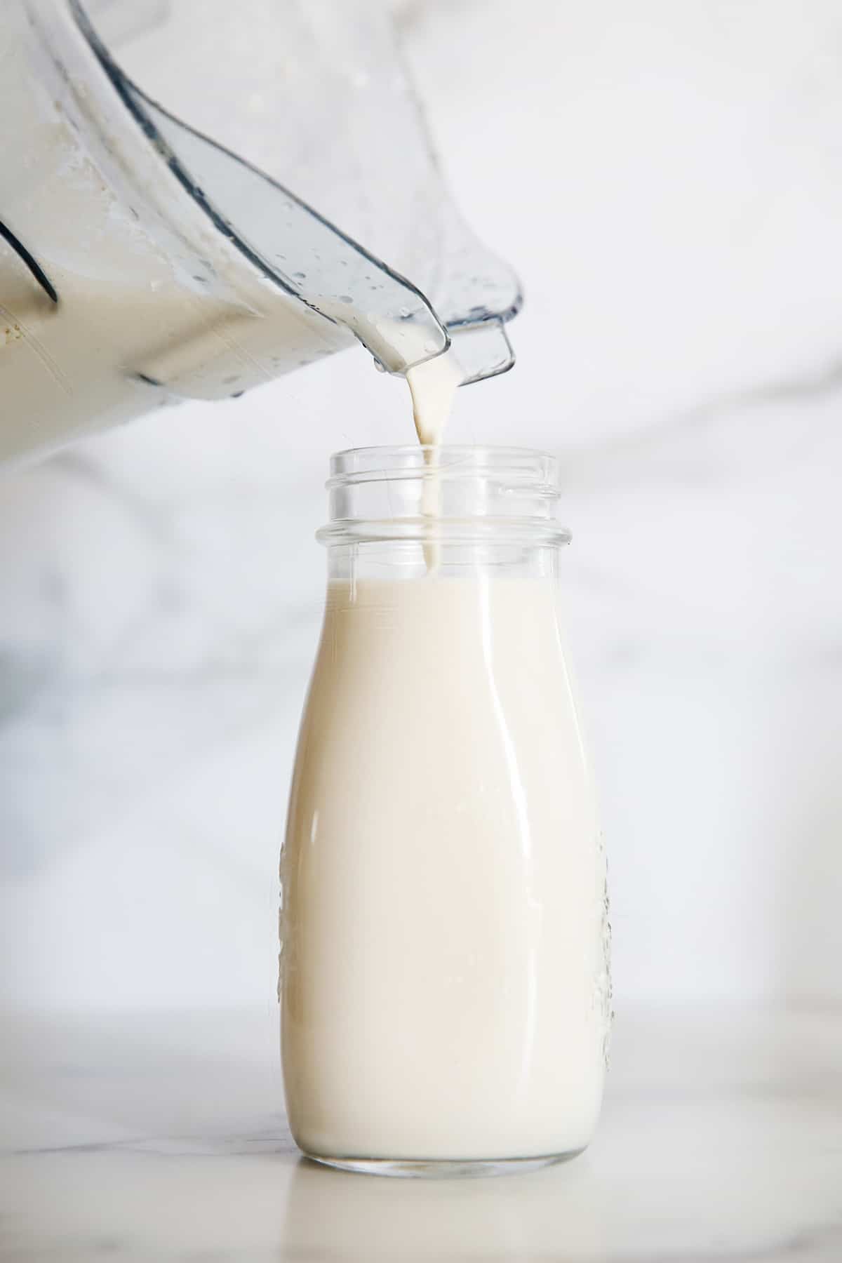 pouring finished cashew milk recipe into a glass jar