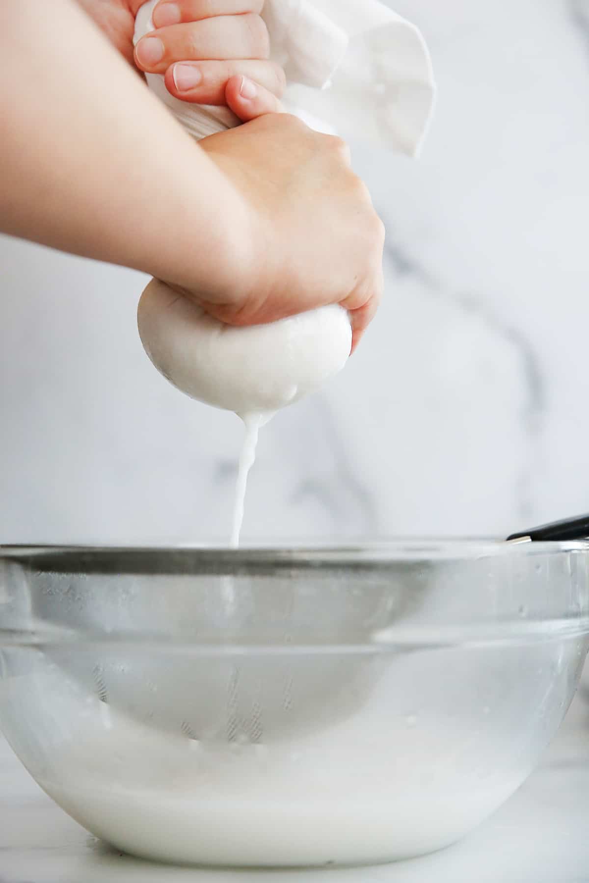 squeezing homemade almond milk in a strainer
