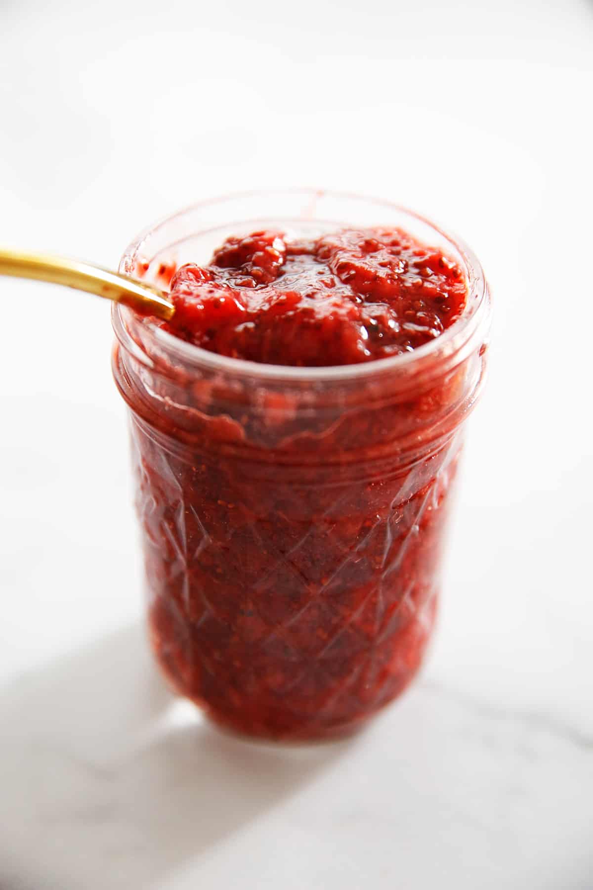 A spoon sticking out of a jar of chia seed jam. 