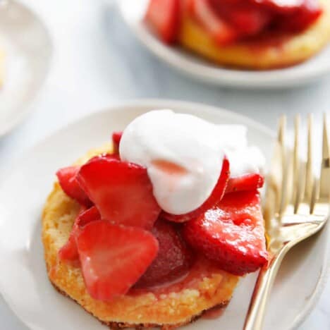 Strawberry shortcake on a plate with chipped cream and a biscuit.