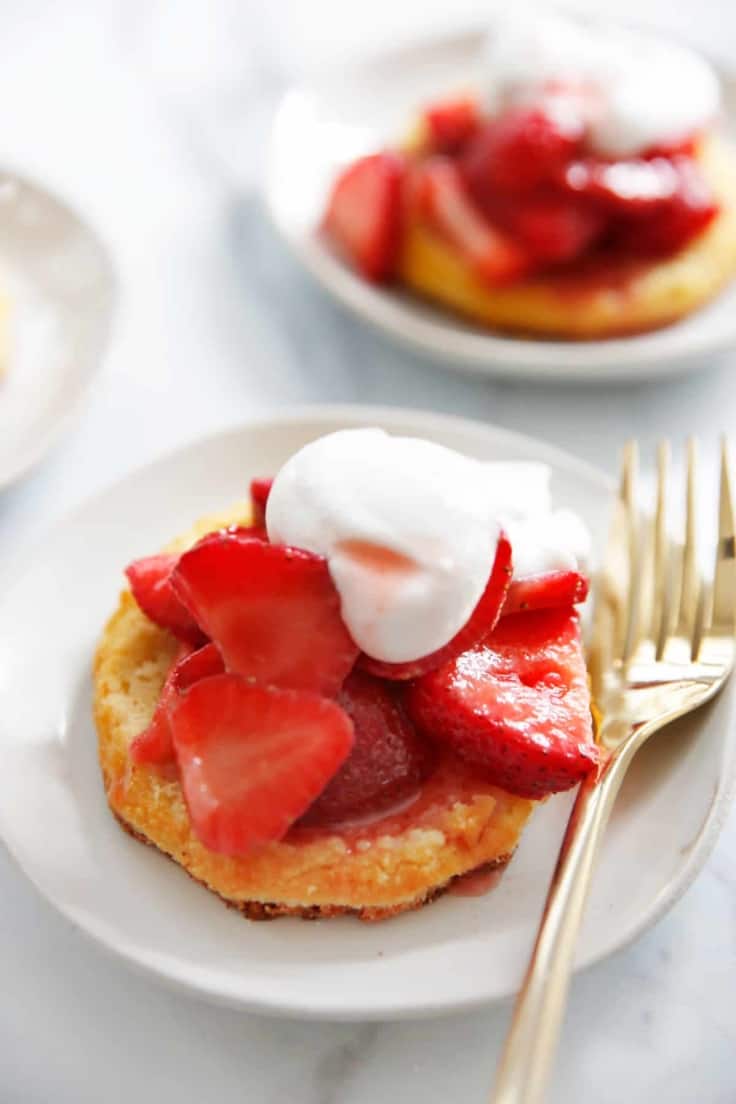 Strawberry shortcake on a plate with chipped cream and a biscuit.