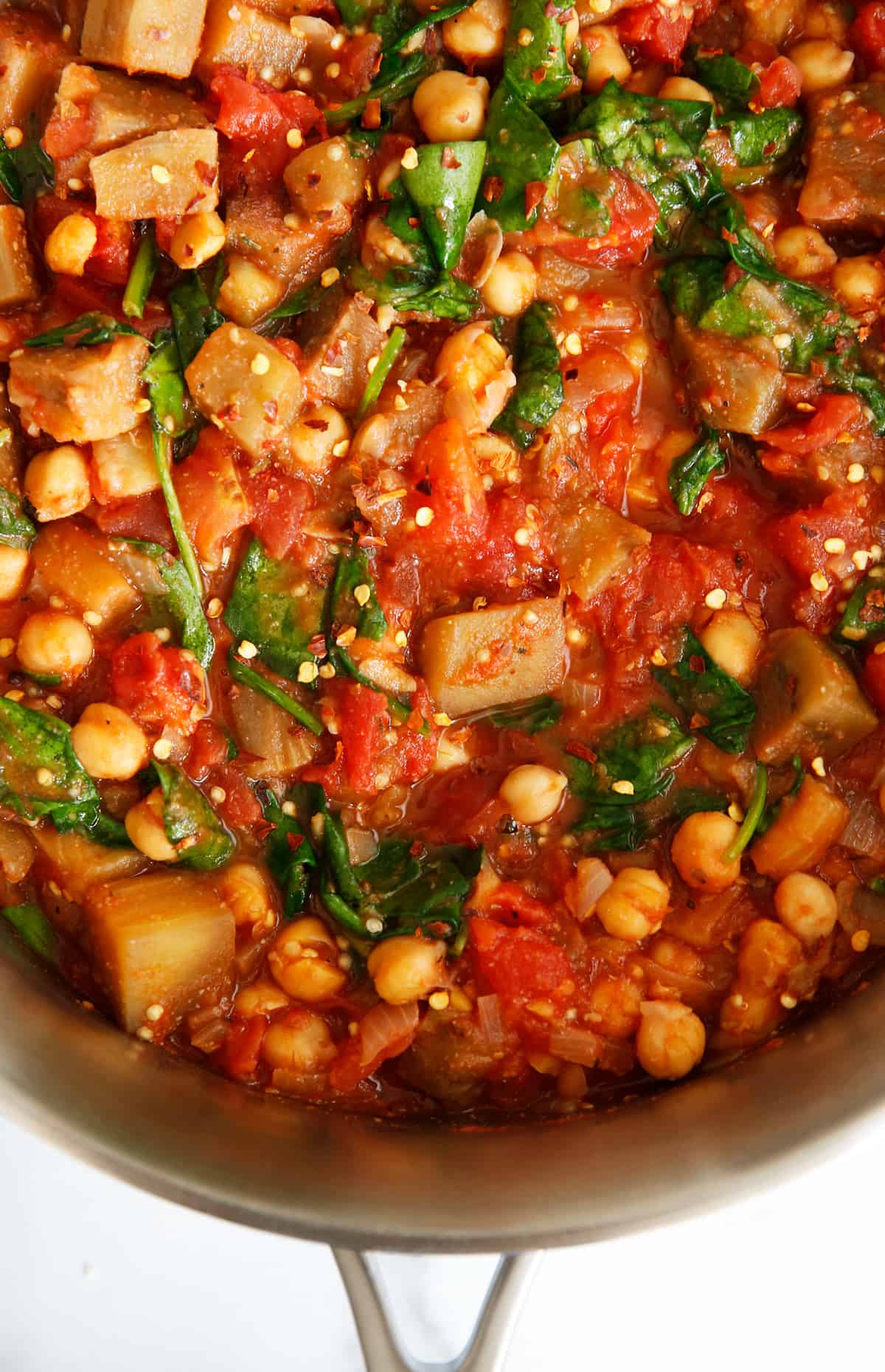 Tomato and eggplant chickpea stew in pot with spinach