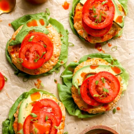 four buffalo chicken burgers topped with tomato from above.