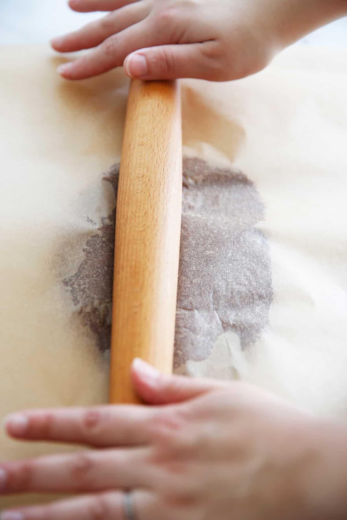 almond flour cracker dough being rolled out by hand