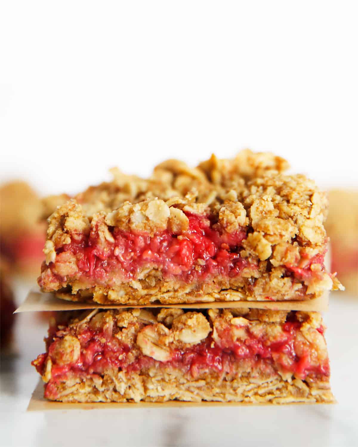 Two raspberry granola bars are stacked on top of each other.