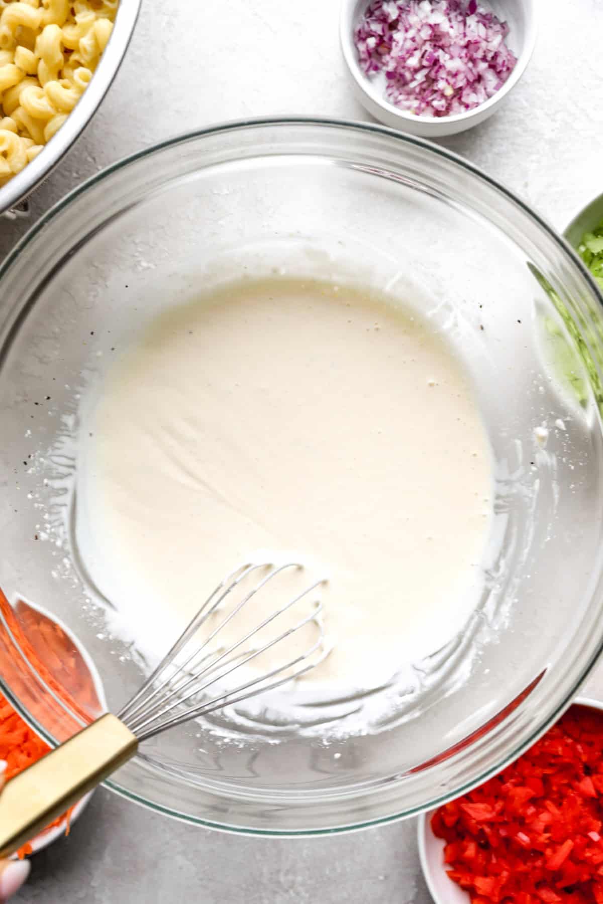 mayo dressing for pasta salad in a mixing bowl with a whisk.