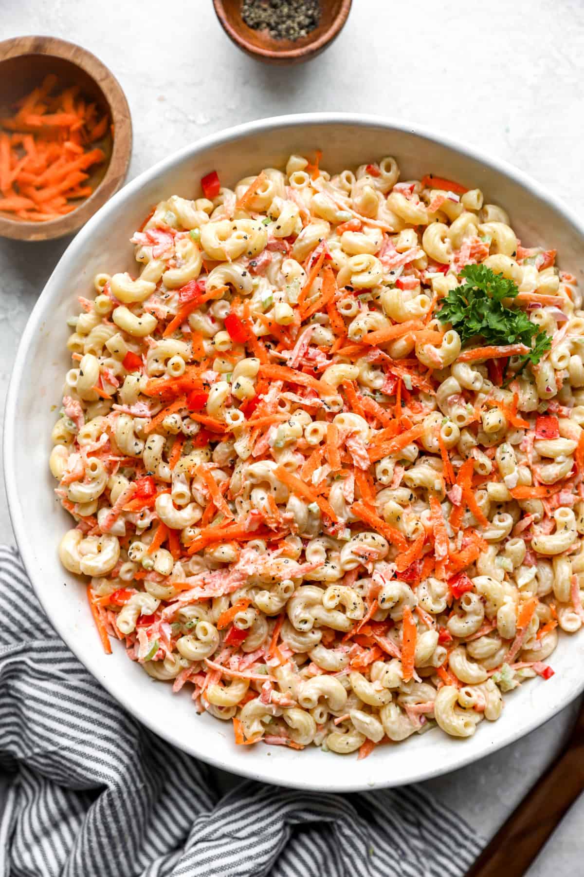 above image of pasta salad in a bowl topped with grated carrots.