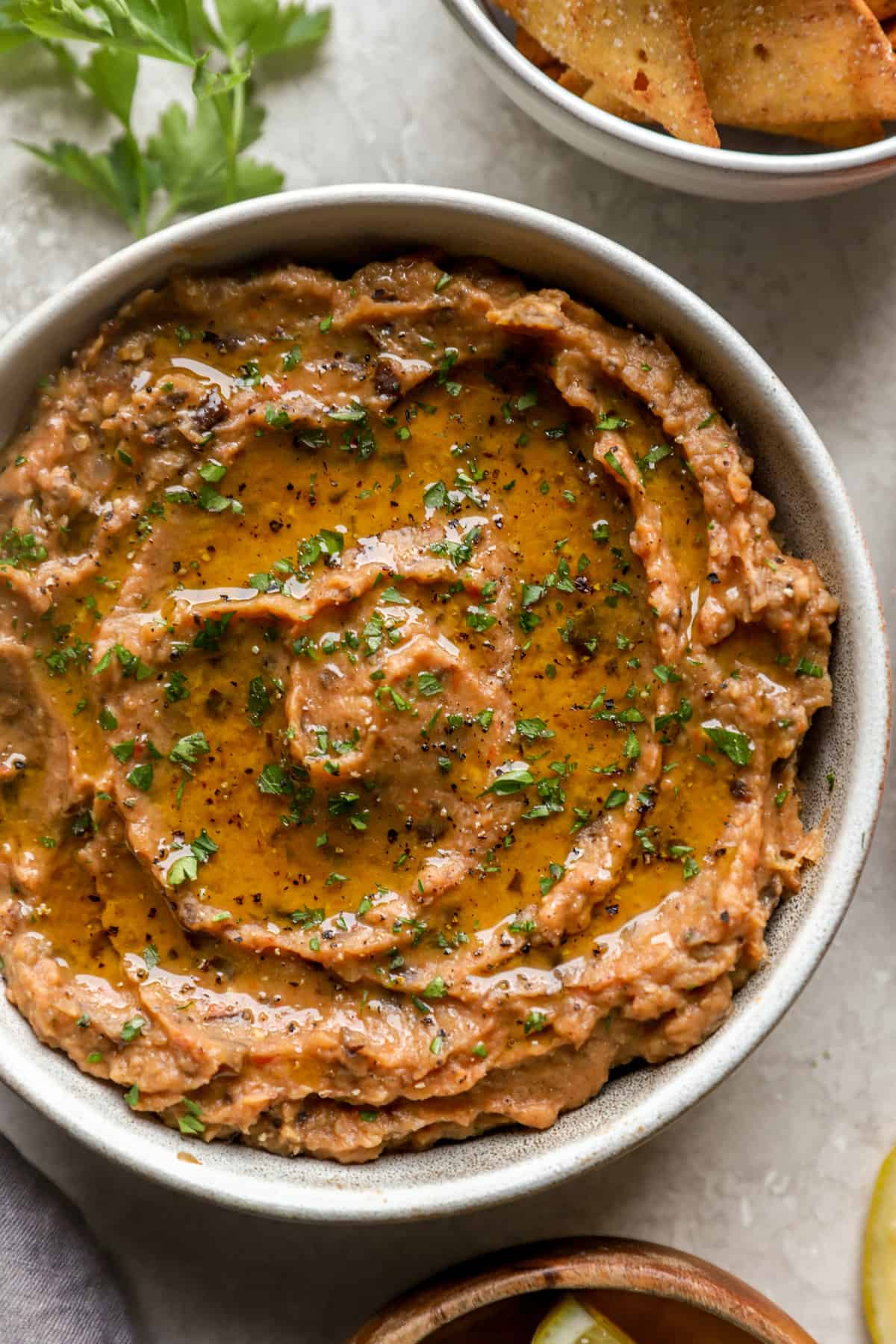 Grilled eggplant dips into bowl from above.