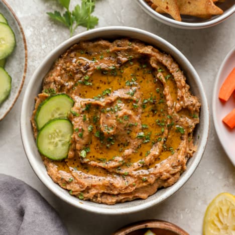 above image of a bowl of eggplant dip garnished with two slices of fresh cucumber.