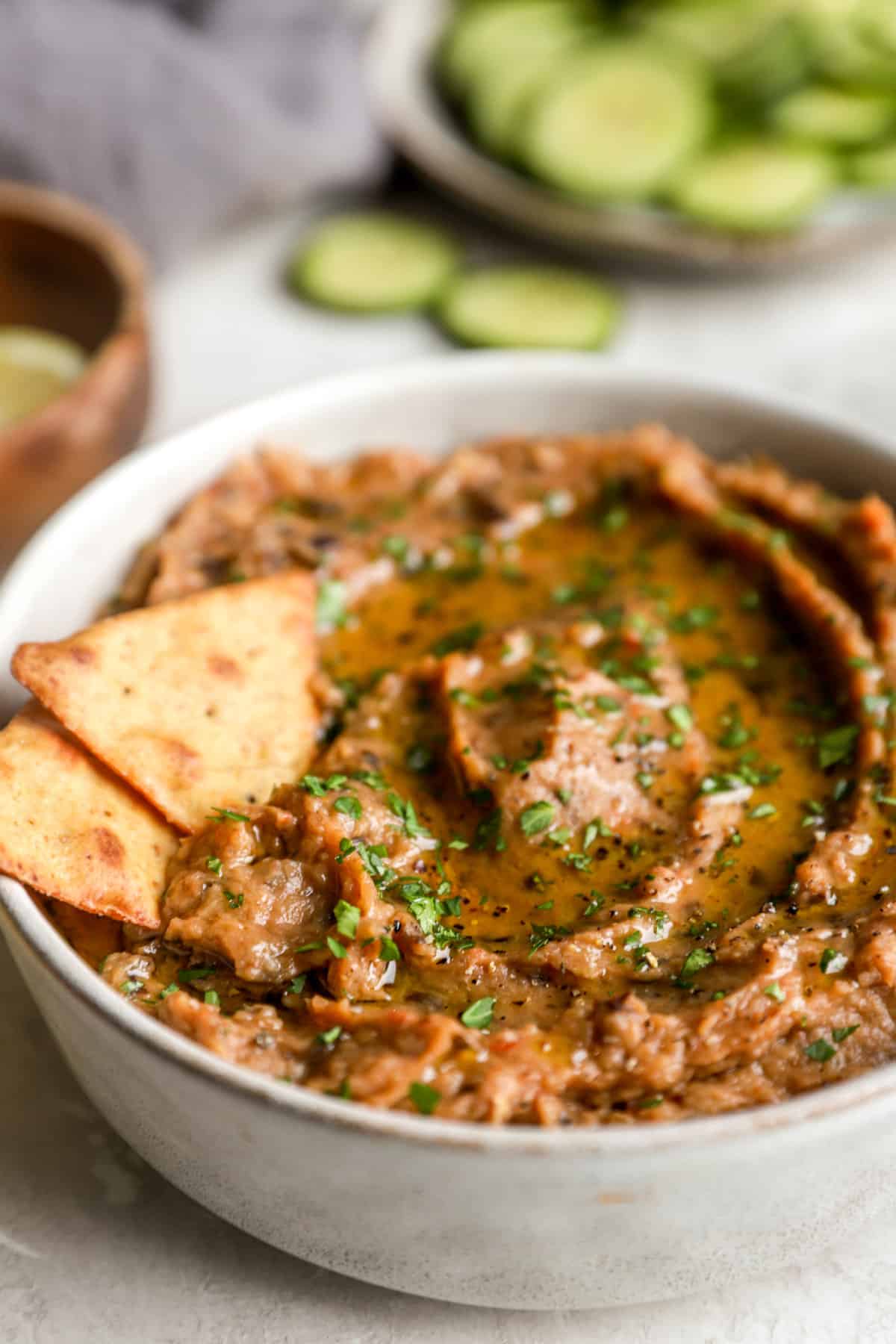 Side view of a bowl of grilled eggplant dip and two crackers.