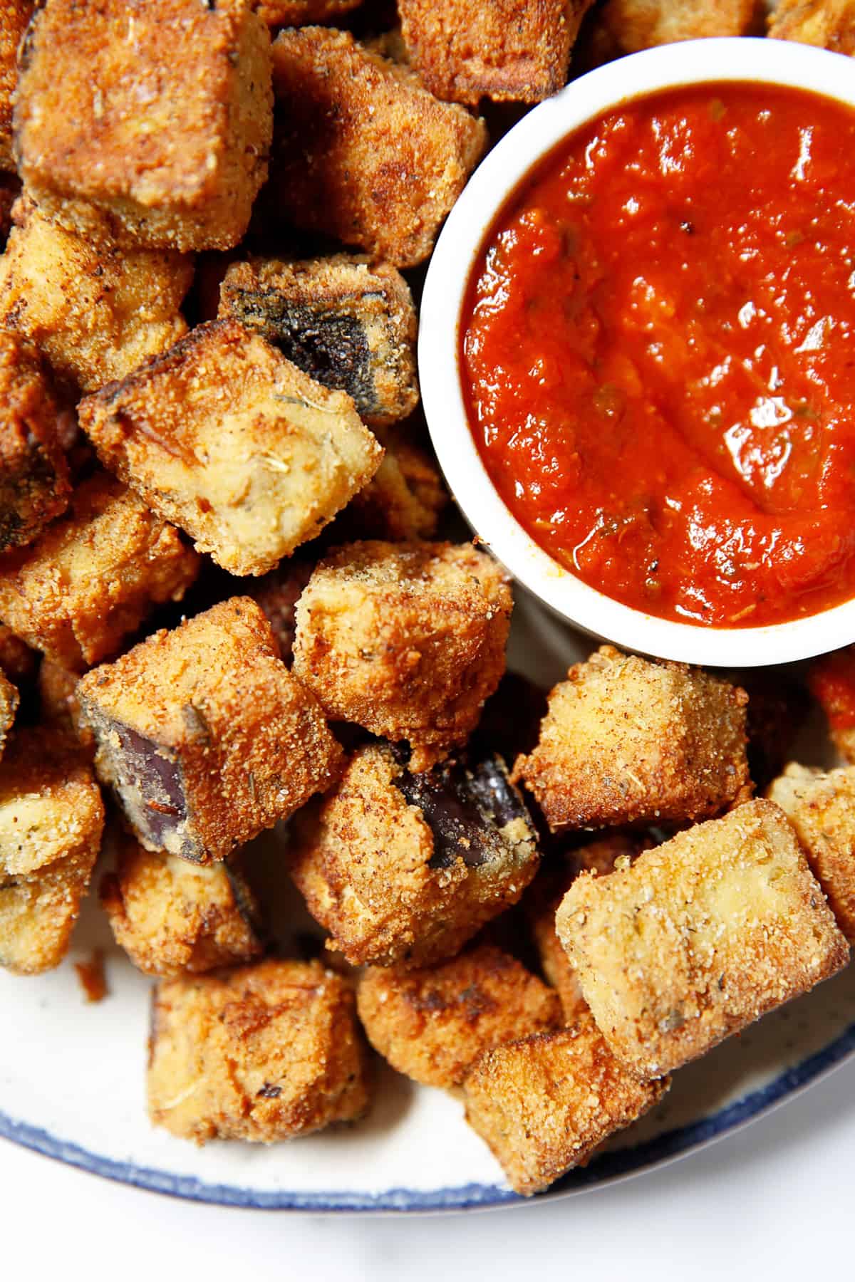 Tasty eggplant Parm bites on a plate with dipping sauce