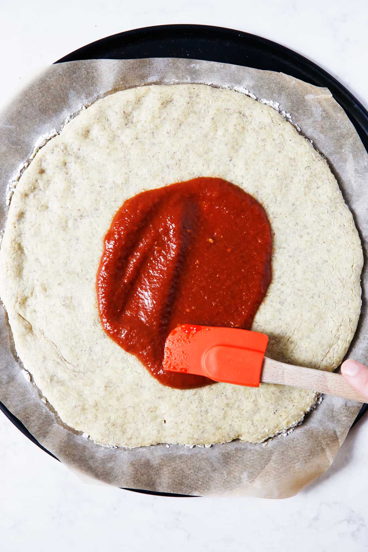 Spreading bbq sauce on pizza crust