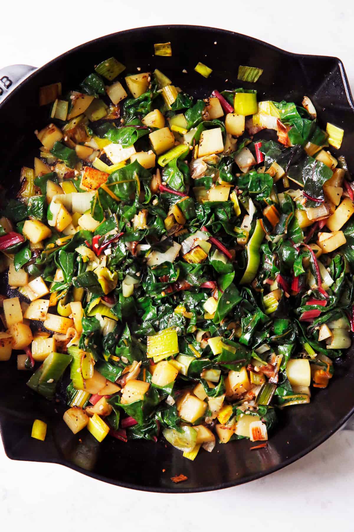 Potato, leek and chard for a frittata in a pan.