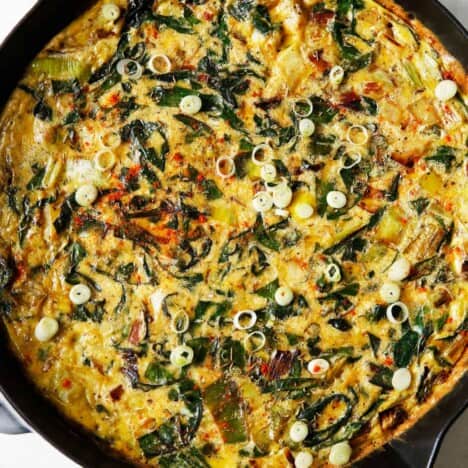 A frittata in a cast iron skillet with potatoes and leeks.