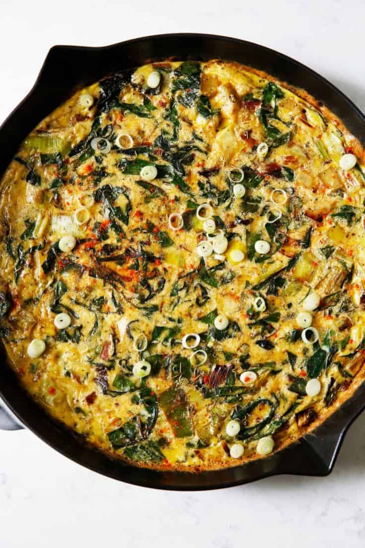 A frittata in a cast iron skillet with potatoes and leeks.