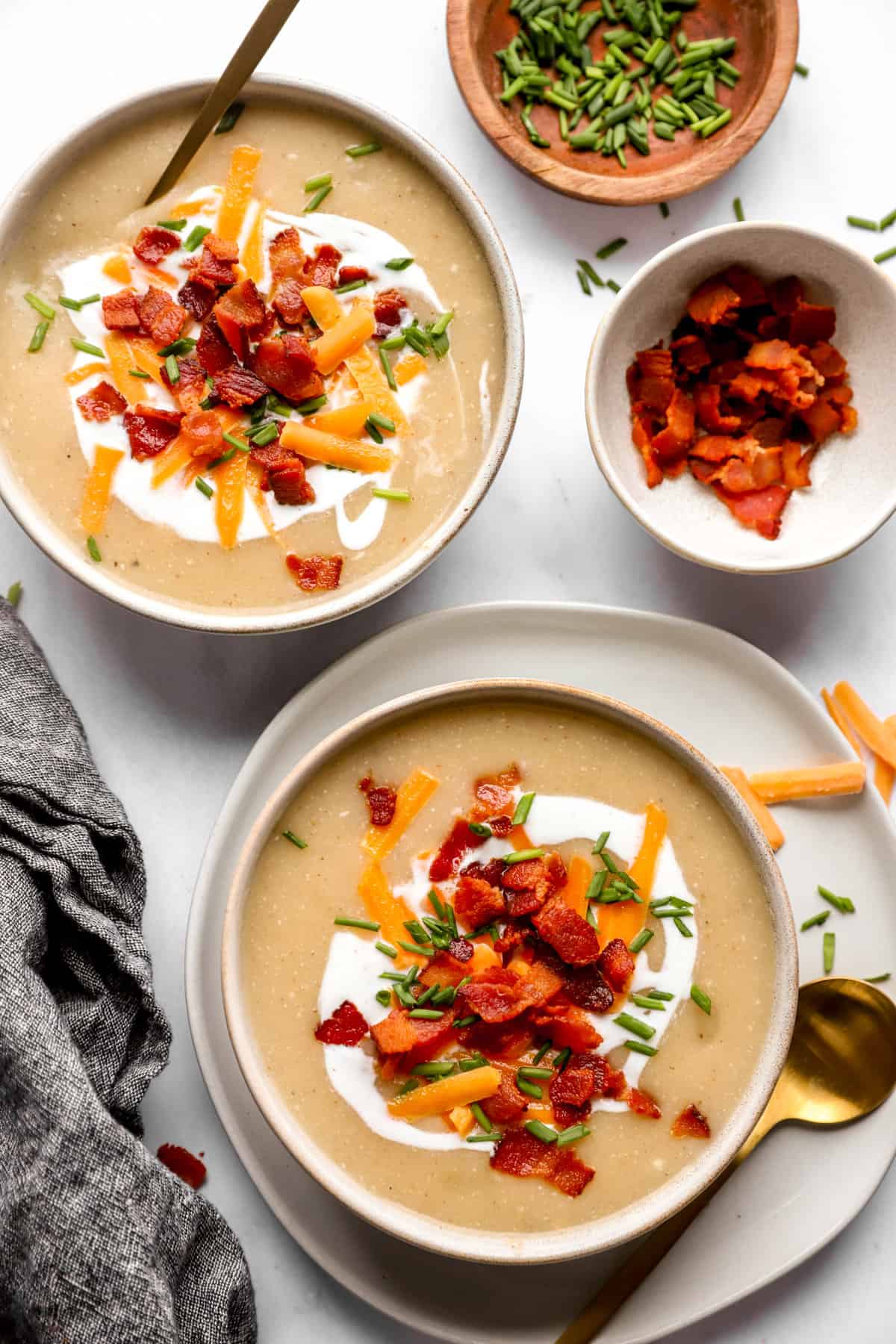 The top two bowls were filled with potato soup, and there was a smaller bowl of bacon slices on the side.