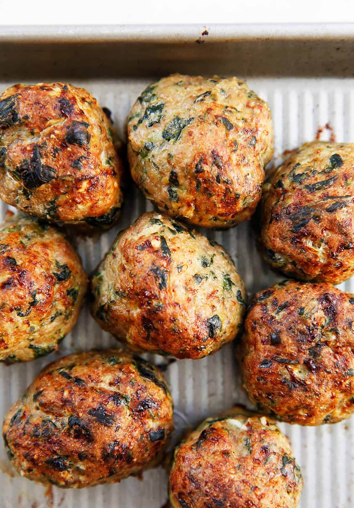 Paleo turkey meatballs with spinach on a sheet pan.