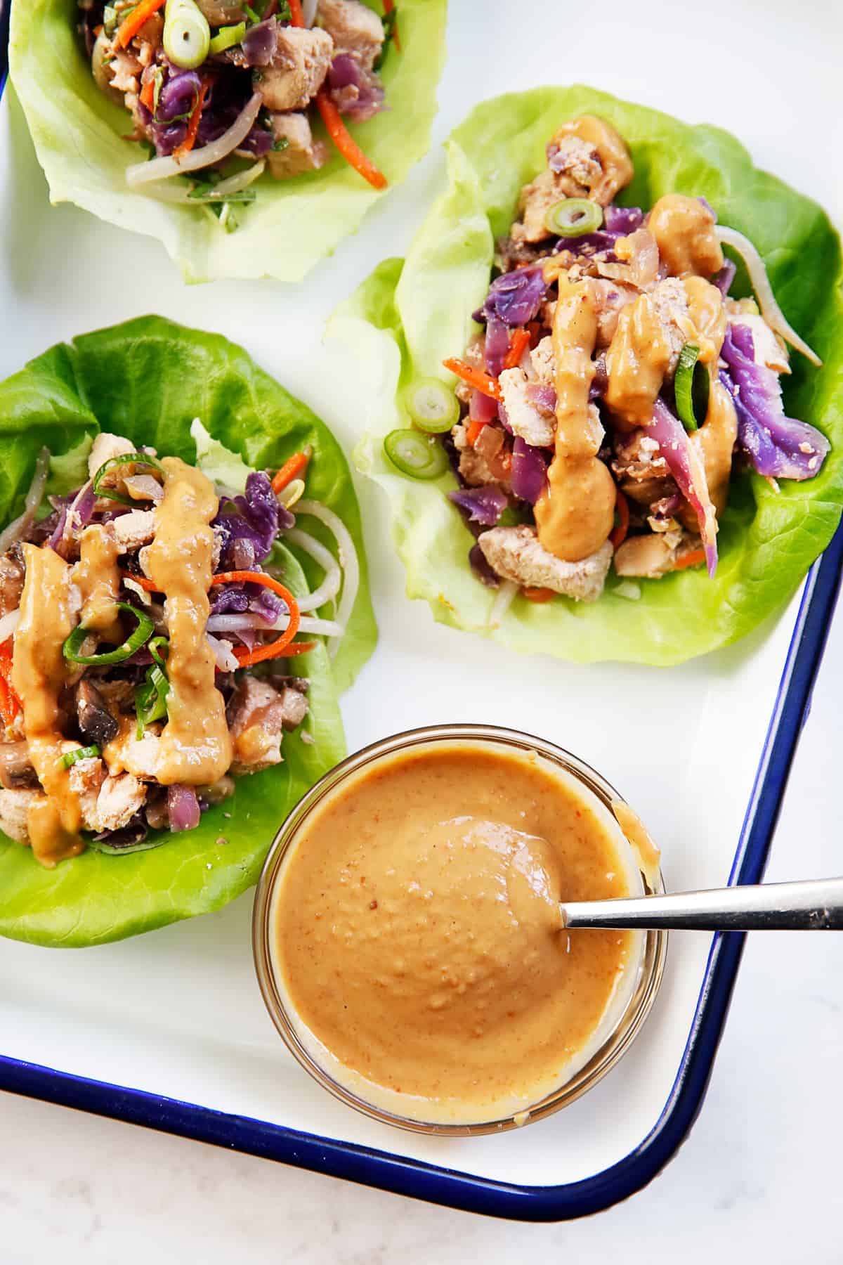 Thai chicken lettuce wraps with peanut sauce on a platter.