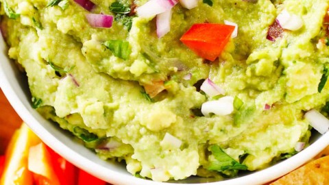 Guacamole with cut vegetables and tortilla chips.