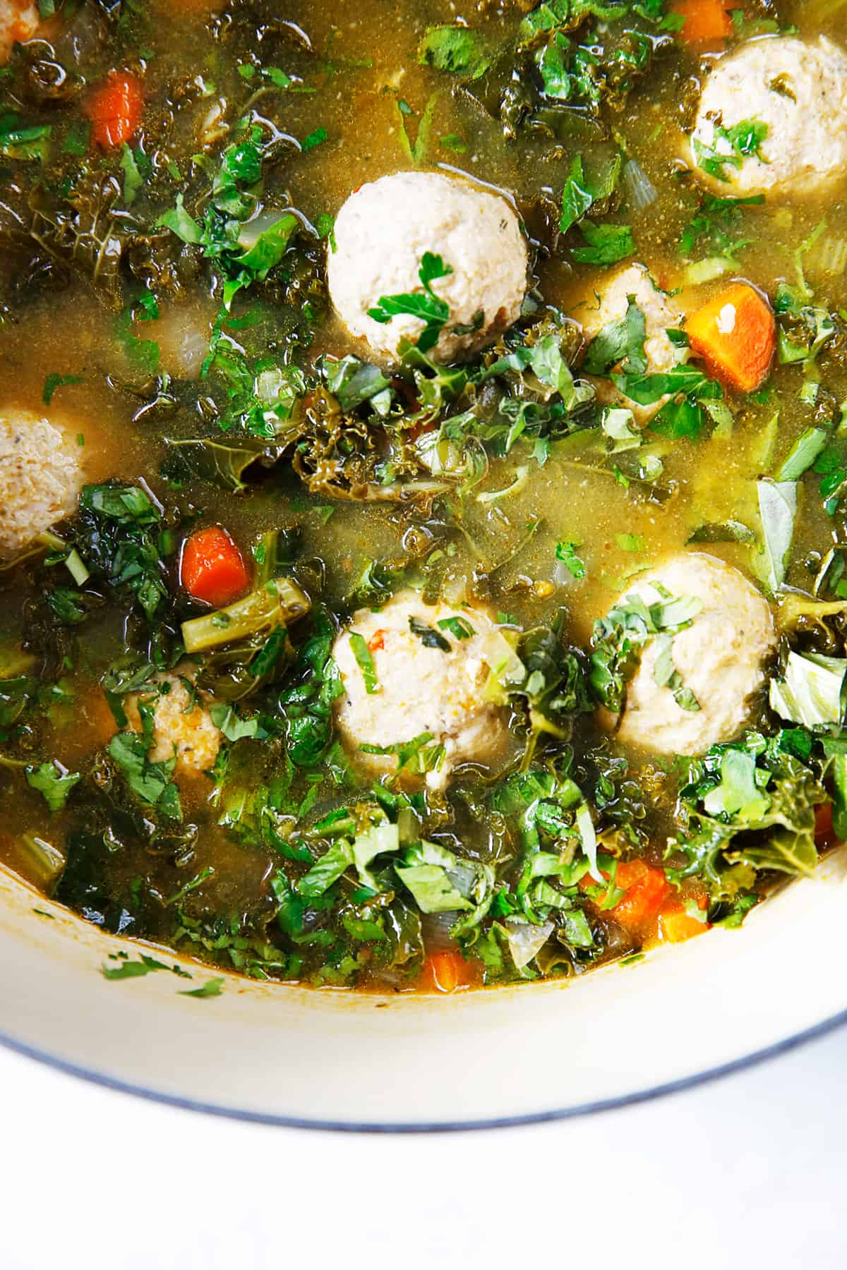 Healthy Italian wedding soup in a pot with ground chicken meatballs and kale.