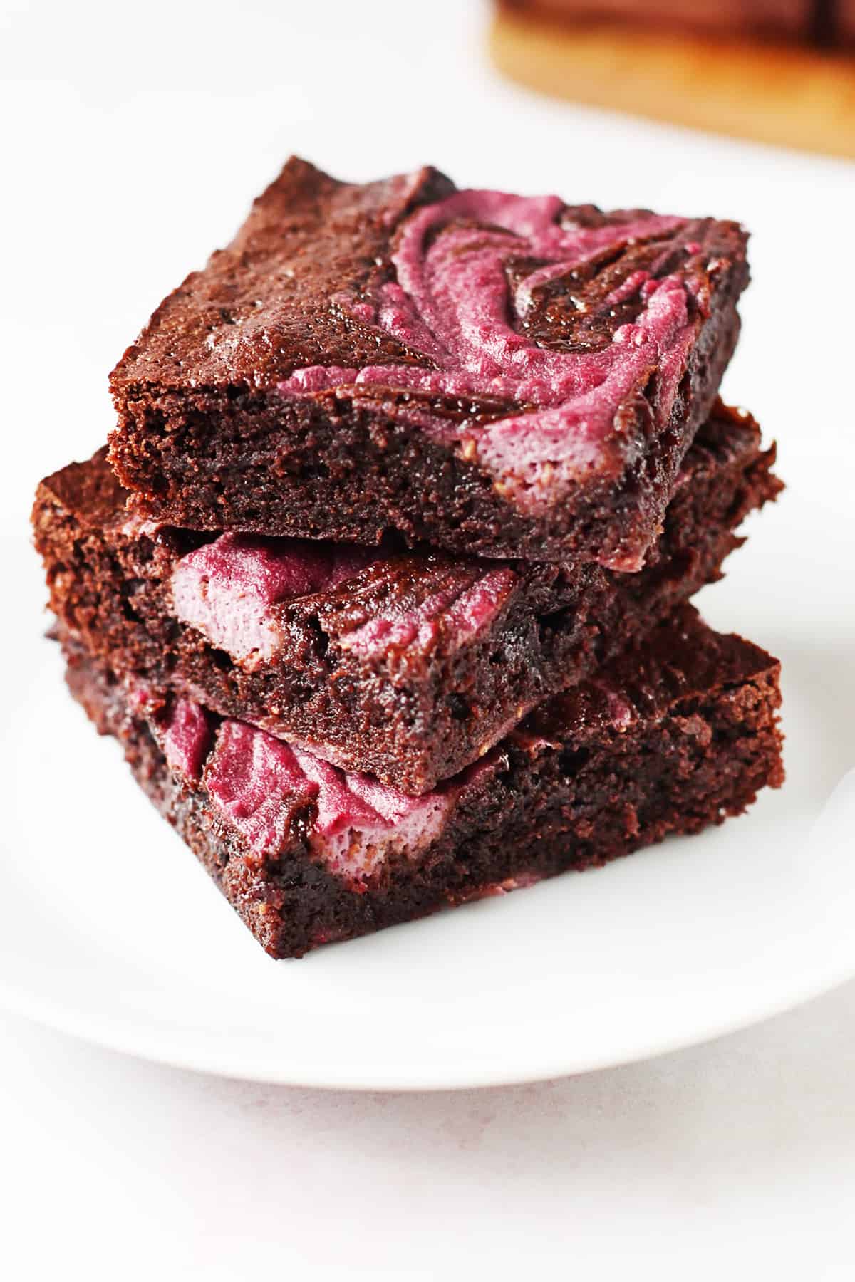 A stack of chocolate raspberry brownies on a plate.