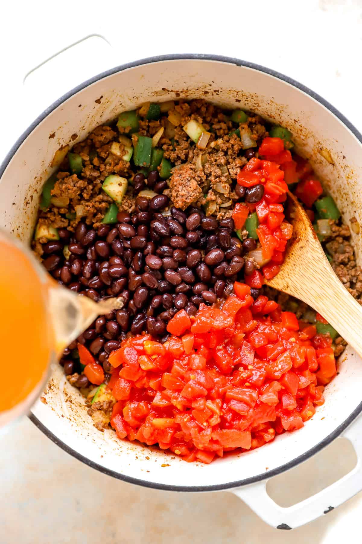 Dutch oven with browned ingredients plus black beans, diced tomatoes, and adding broth.