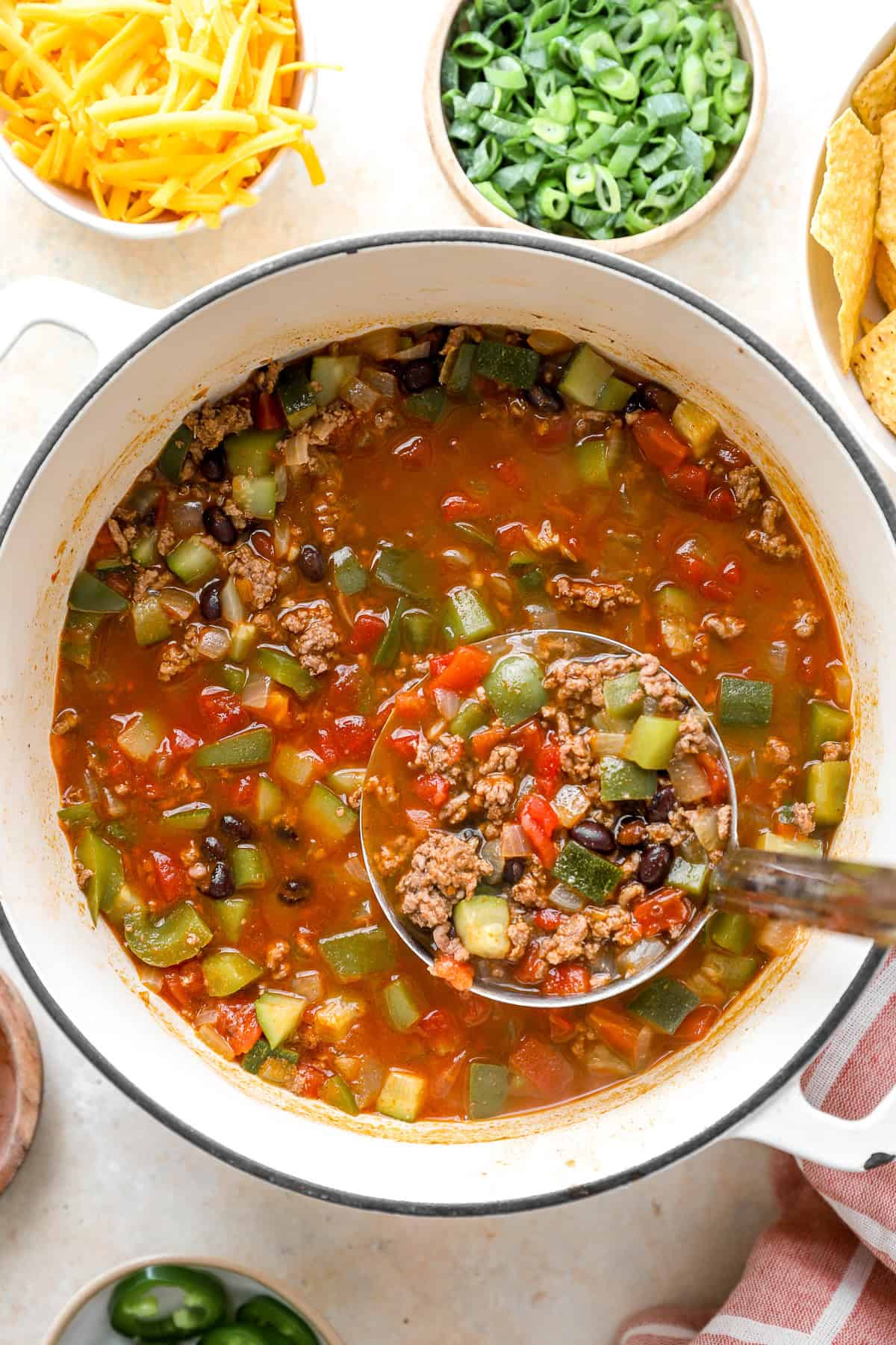 All ingredients simmering in a dutch oven with a ladle.