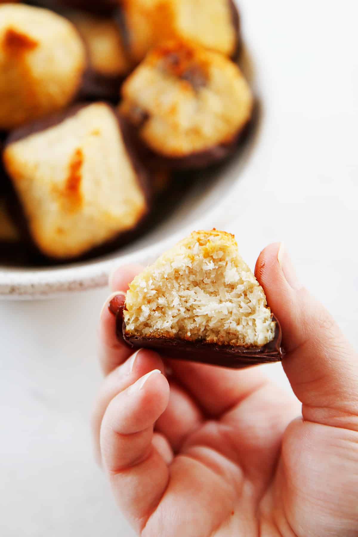 A bite of a healthy coconut macaroon dipped in chocolate.