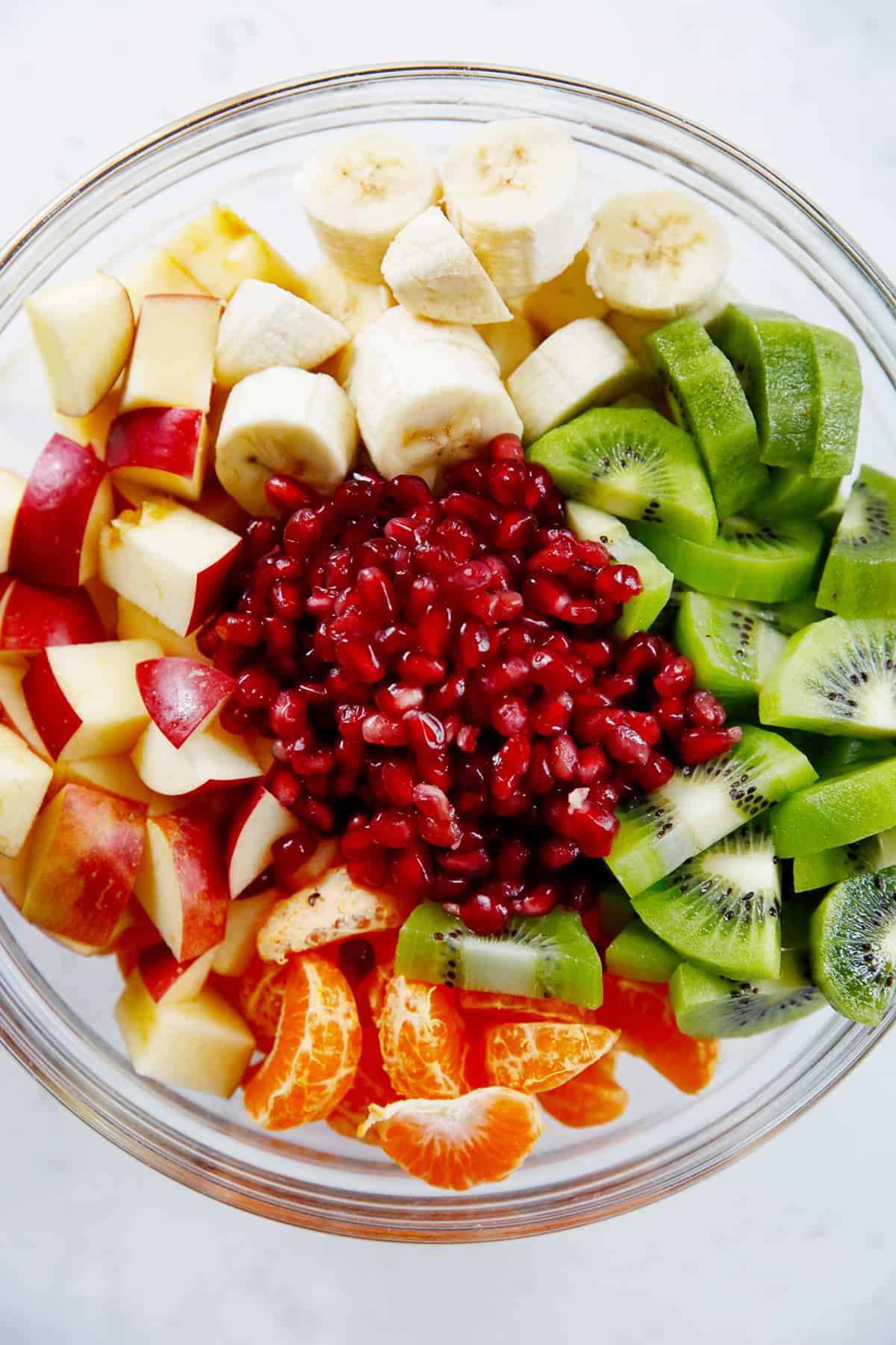 Winter fruit salad with pomegranate, kiwi, banana, apples and clementines.