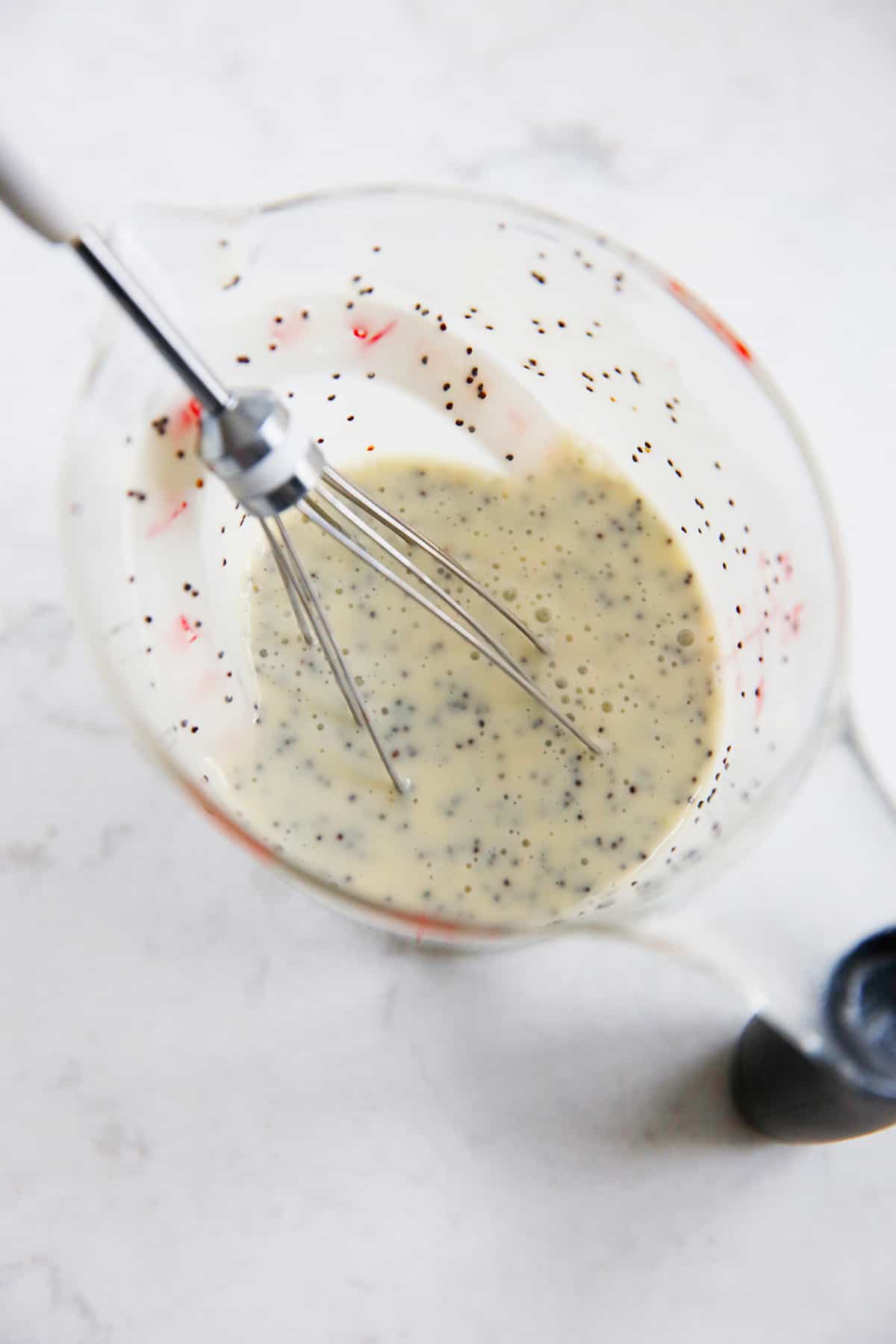 Greek yogurt dressing for fruit salad in a measuring cup with a whisk.
