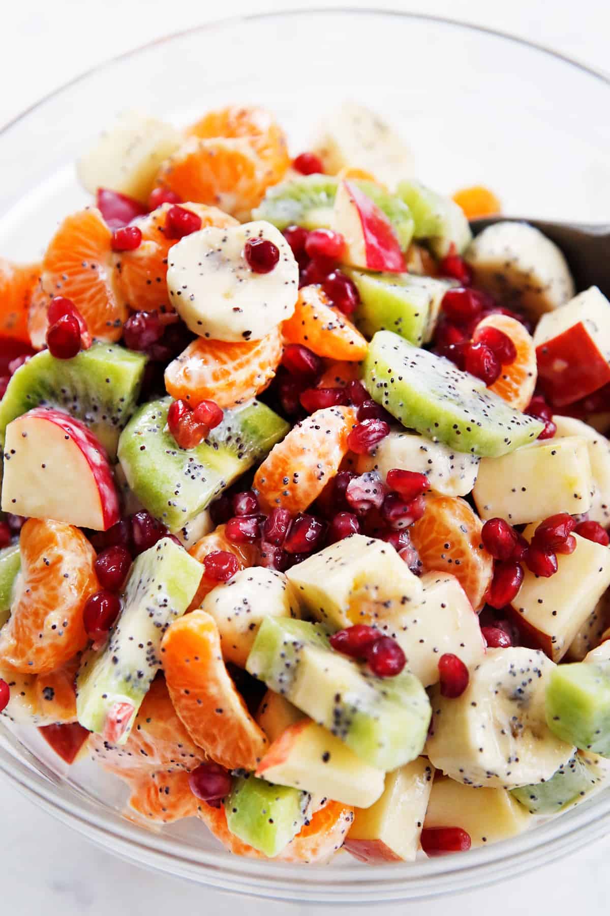 closeup image of a winter fruit salad tossed in yogurt dressing in a bowl.