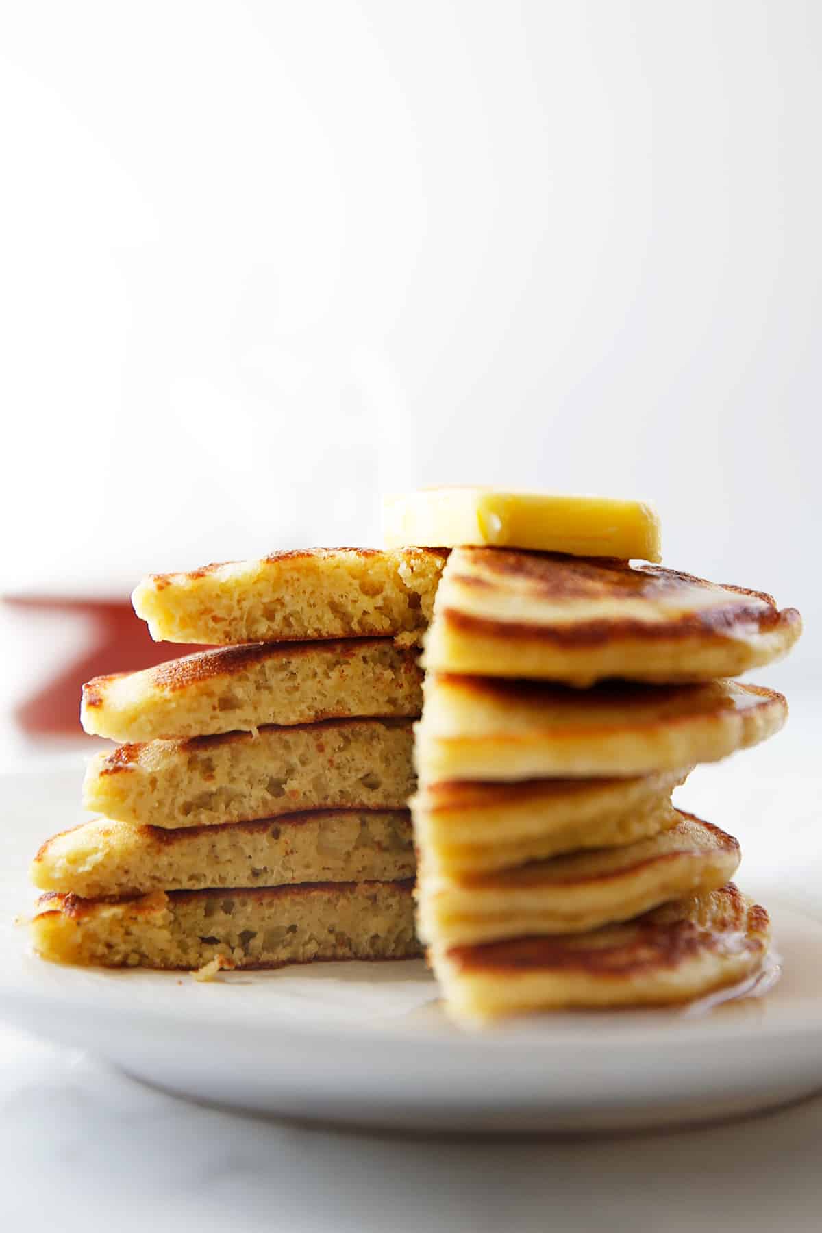 A stack of paleo pancakes with a slice taken out of them.