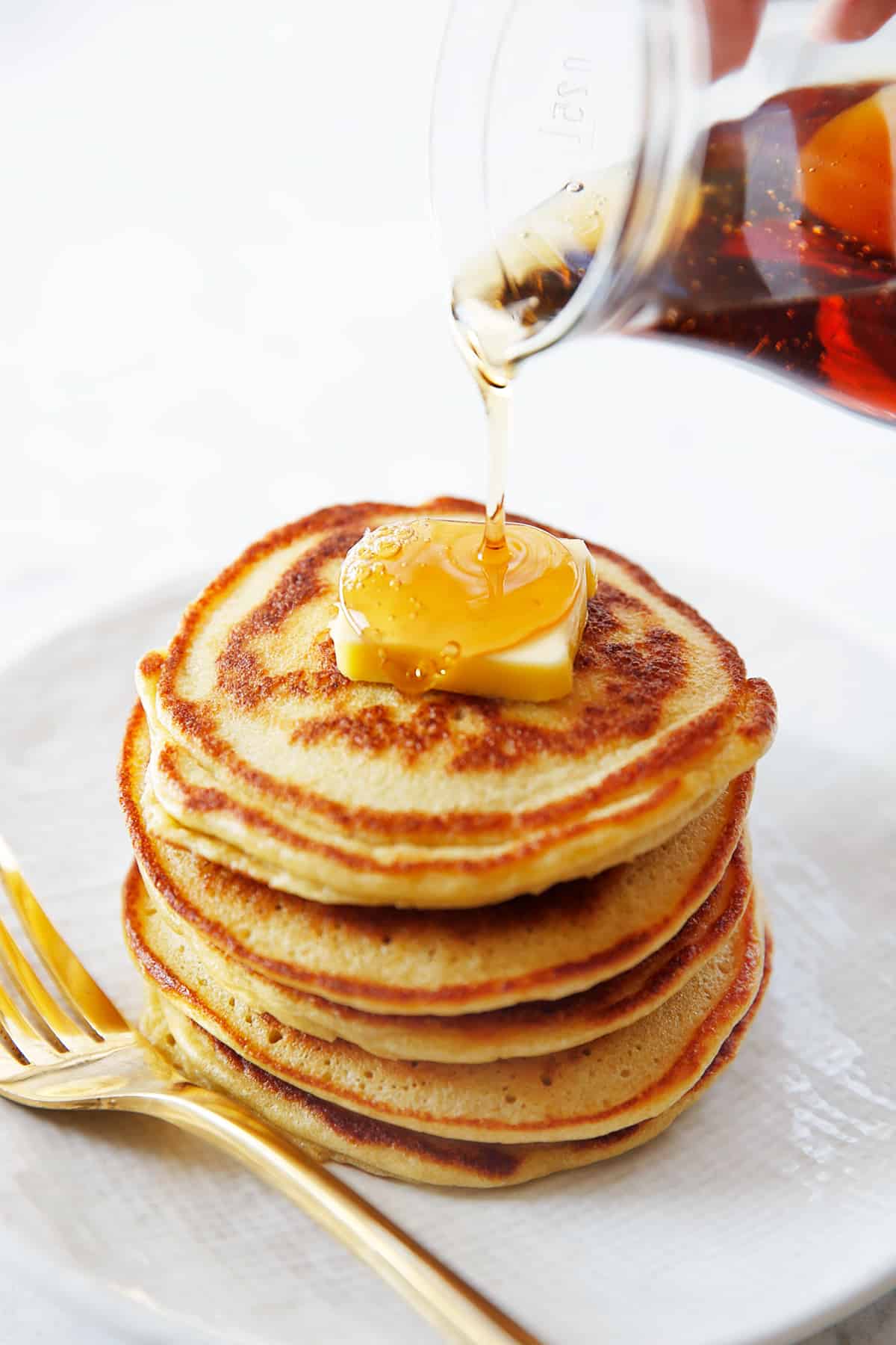 A stack of fluffy paleo pancakes woith a pour of syrup