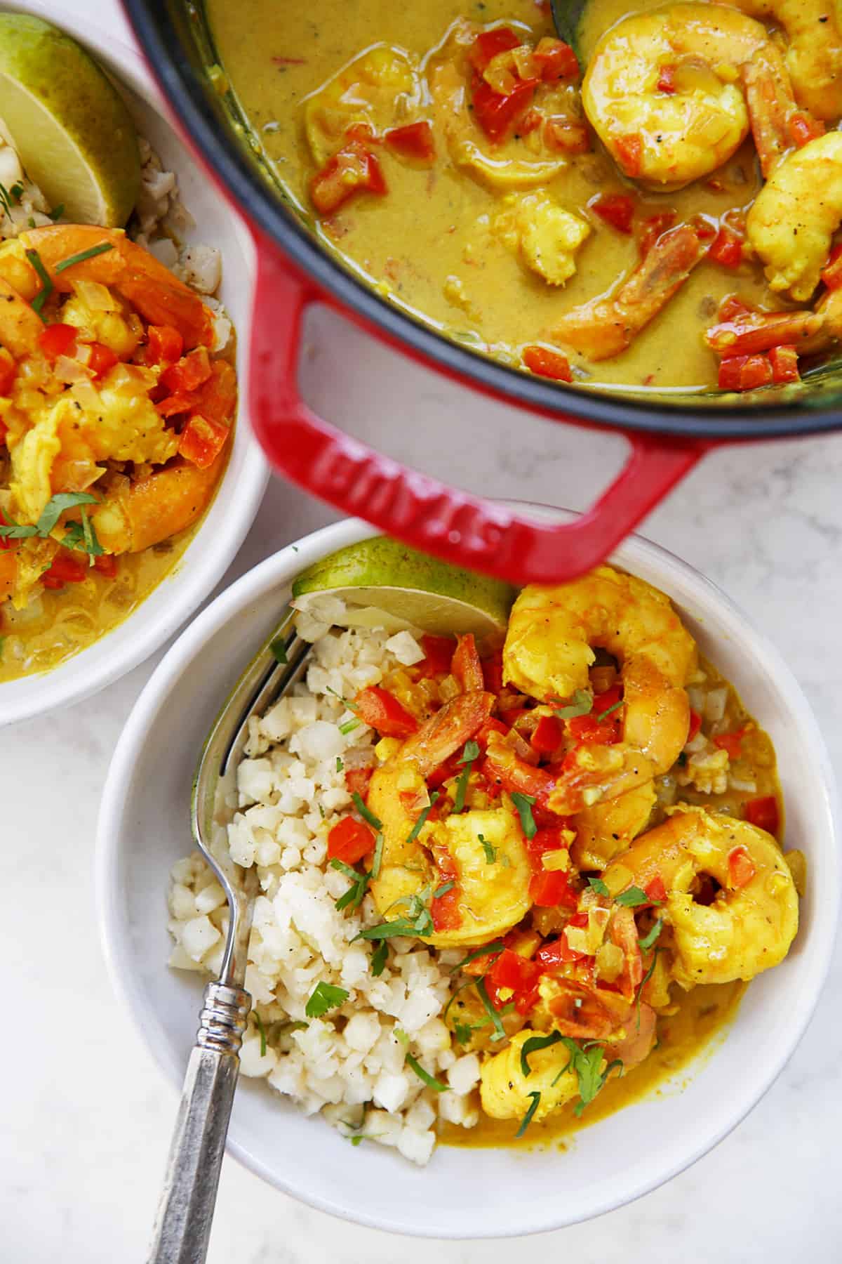 A table set with a meal of yellow shrimp curry in bowls.